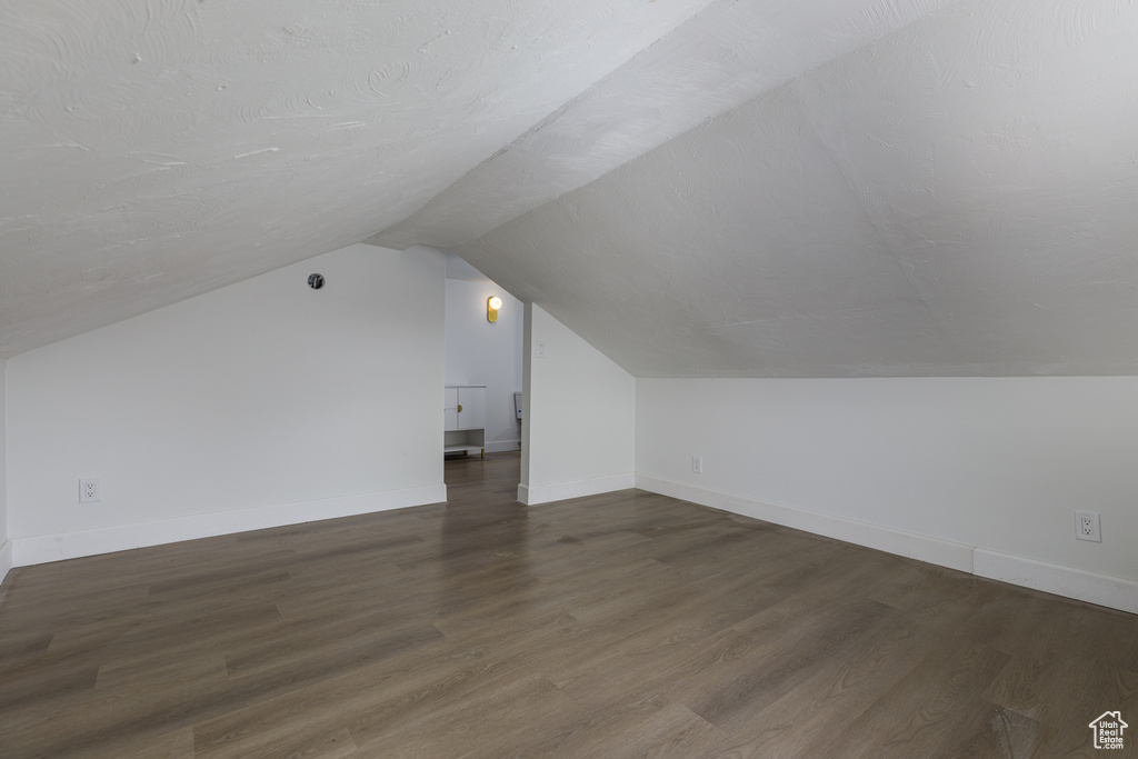Additional living space with vaulted ceiling and dark hardwood / wood-style floors