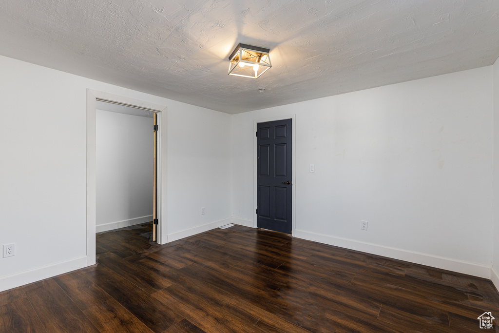 Empty room featuring dark hardwood / wood-style floors and a textured ceiling