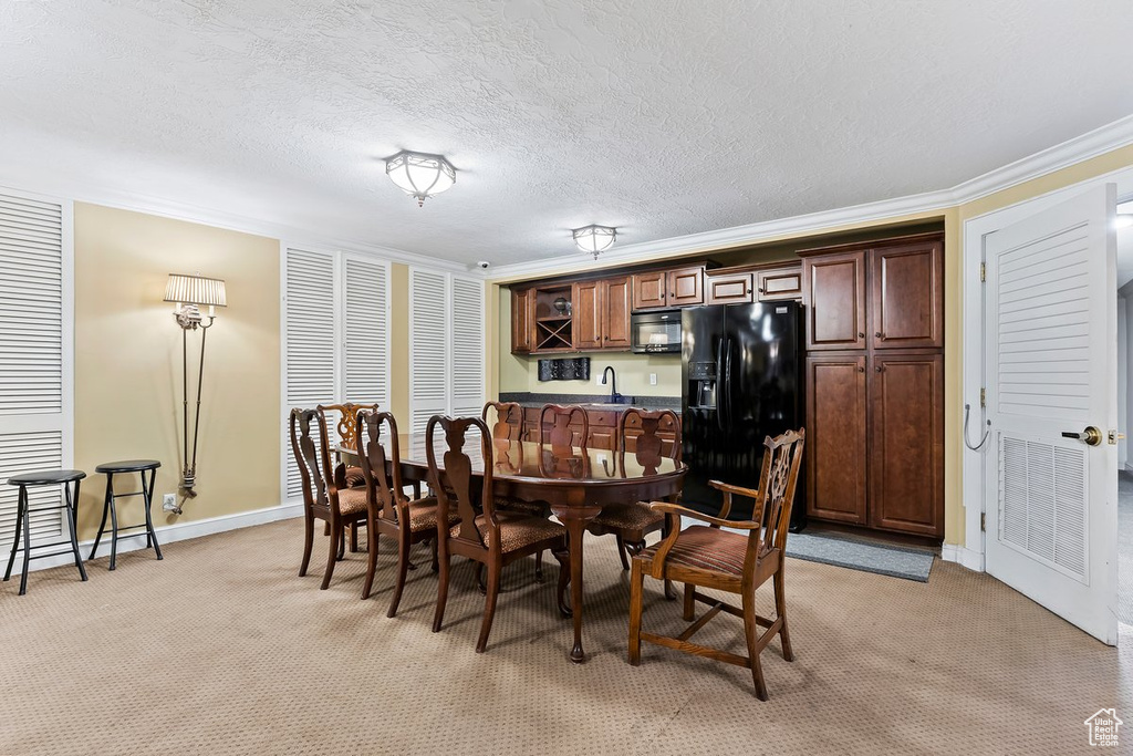Dining area featuring ornamental molding, light colored carpet, a textured ceiling, and sink