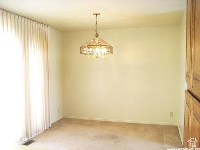 Empty room with a notable chandelier and light colored carpet
