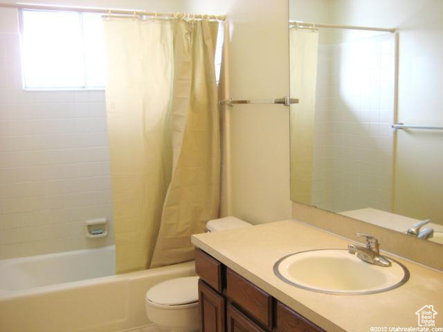 Full bathroom featuring shower / tub combo with curtain, toilet, and vanity