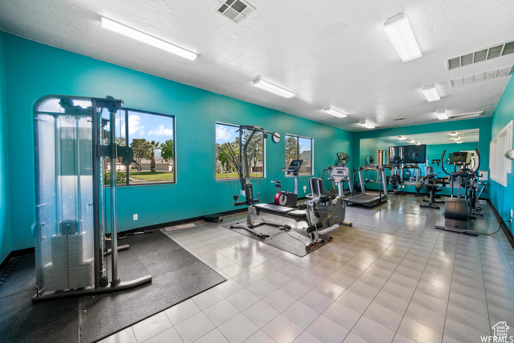Gym featuring a textured ceiling and light tile flooring