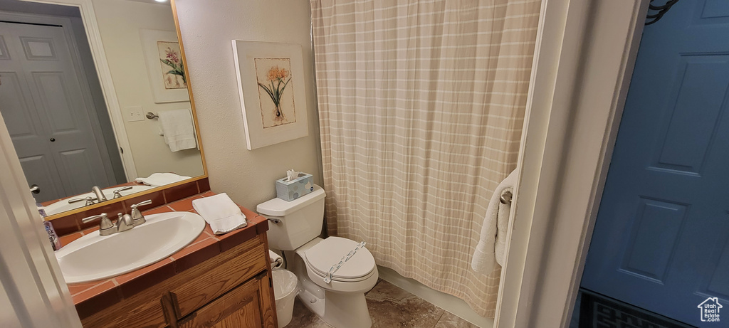 Bathroom featuring tile walls, toilet, vanity with extensive cabinet space, tasteful backsplash, and tile flooring