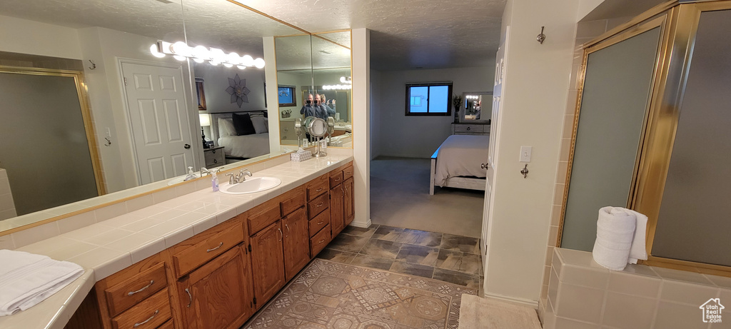 Bathroom featuring tile floors, vanity with extensive cabinet space, and a textured ceiling