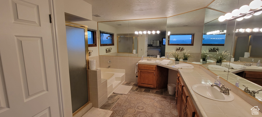 Bathroom with a textured ceiling, tile floors, vanity, and shower with separate bathtub