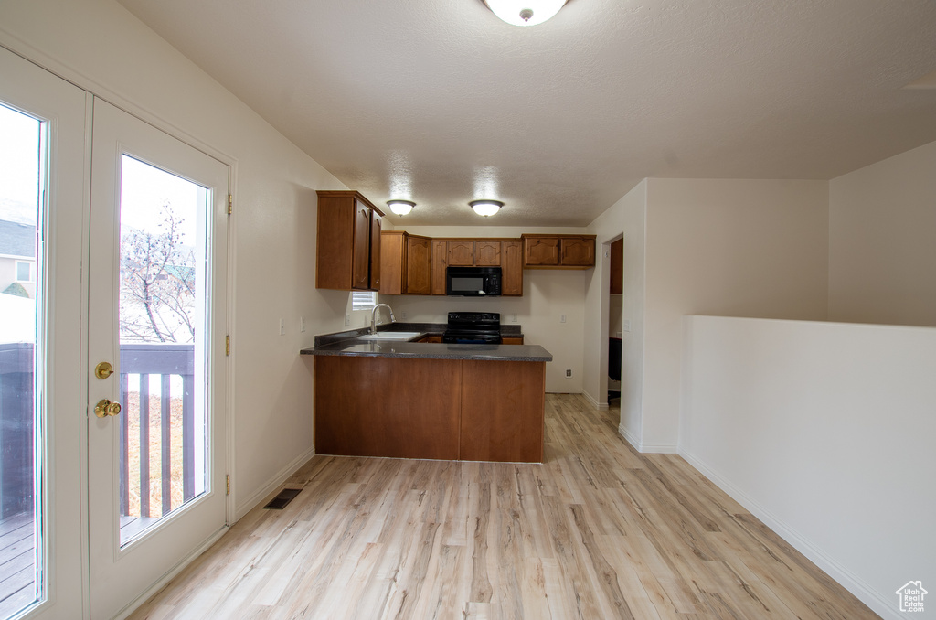 Kitchen featuring sink, light hardwood / wood-style flooring, kitchen peninsula, and black appliances
