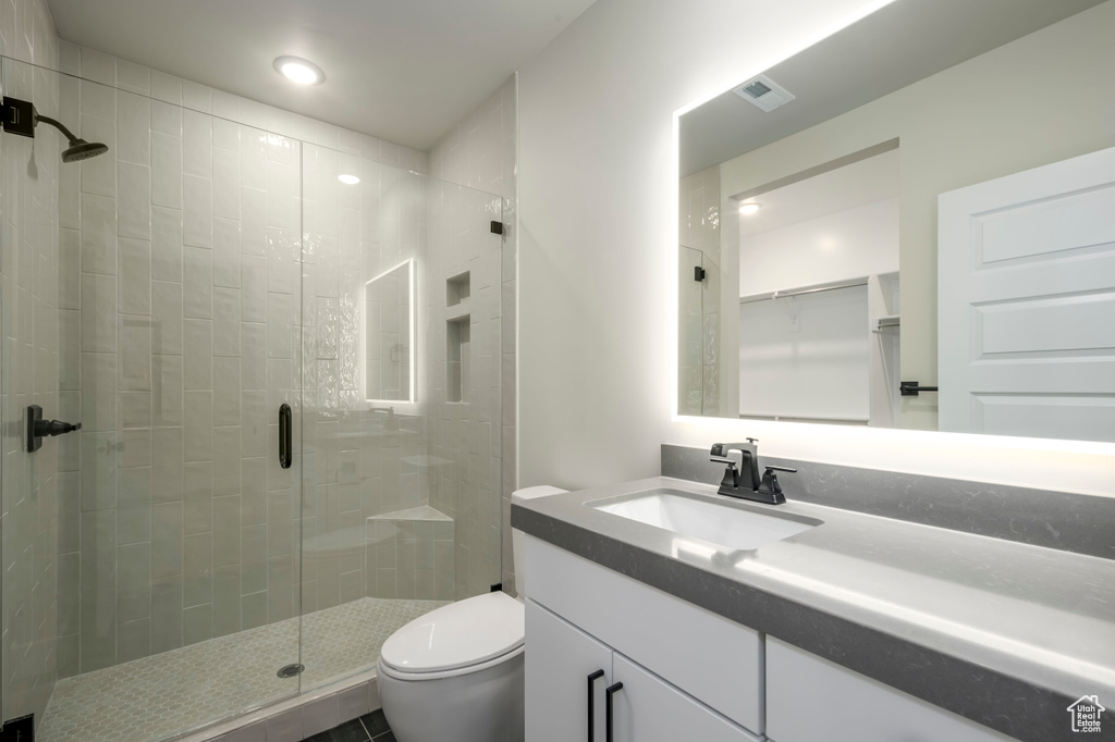 Bathroom featuring a shower with door, toilet, and oversized vanity