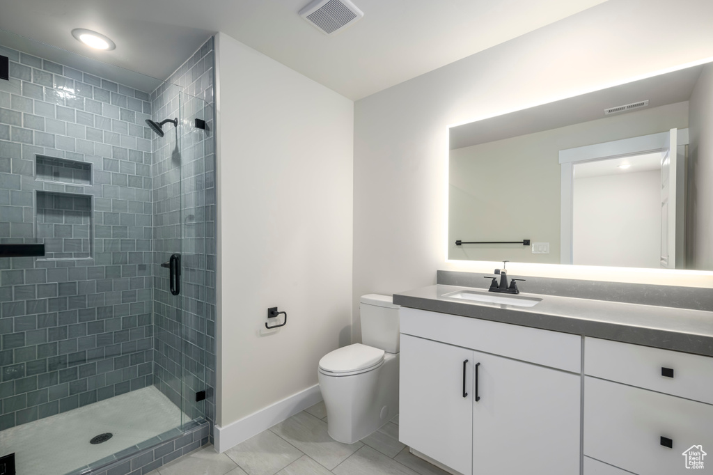 Bathroom featuring oversized vanity, toilet, tile flooring, and walk in shower