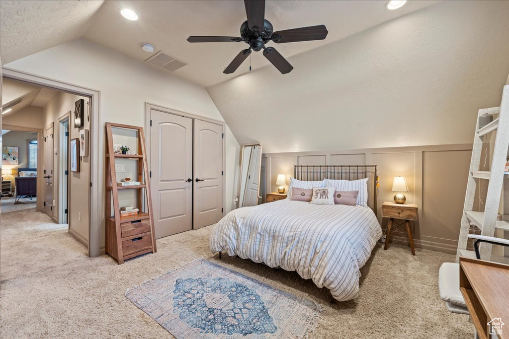 Carpeted bedroom with a closet, a textured ceiling, lofted ceiling, and ceiling fan