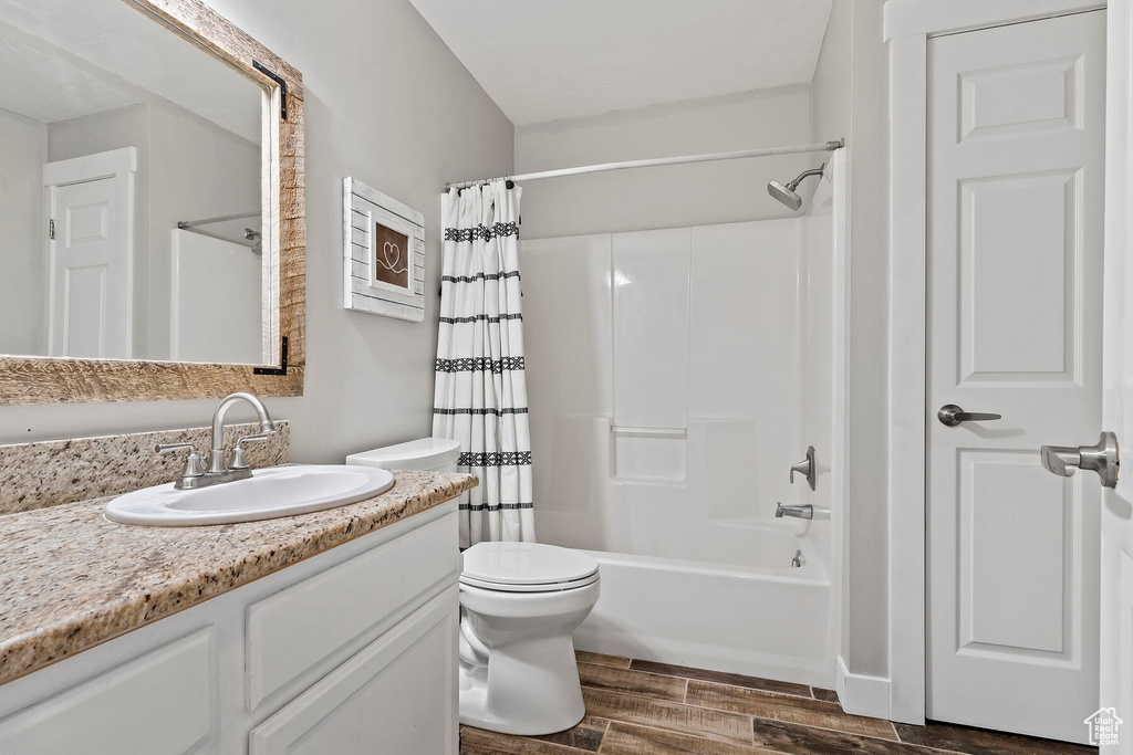 Full bathroom featuring vanity, hardwood / wood-style flooring, toilet, and shower / tub combo with curtain