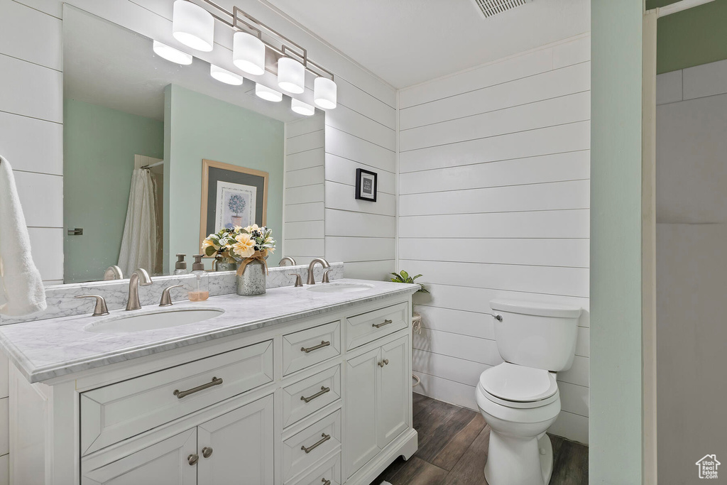 Bathroom with hardwood / wood-style flooring, toilet, and double sink vanity