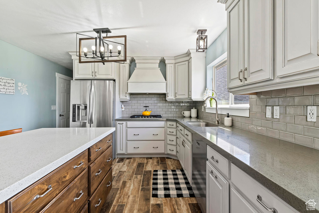 Kitchen featuring white cabinetry, dark hardwood / wood-style flooring, stainless steel appliances, premium range hood, and pendant lighting