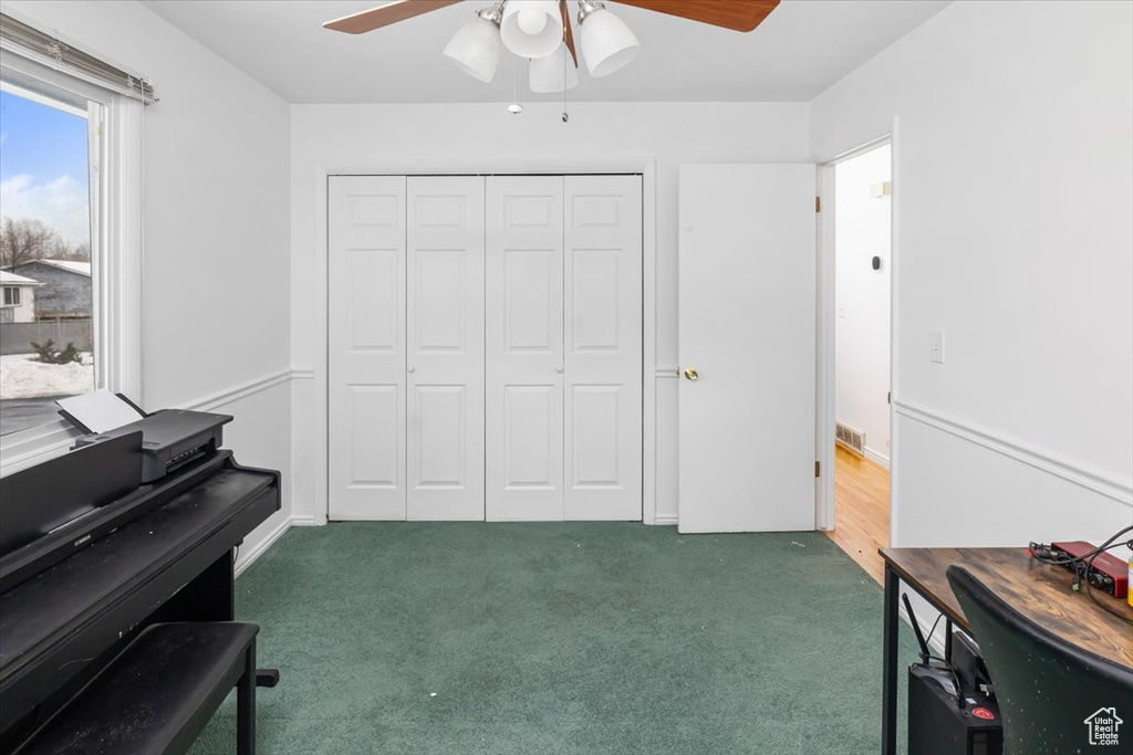 Miscellaneous room with dark colored carpet and ceiling fan