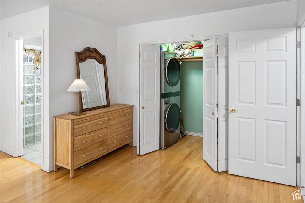 Interior space with stacked washer / drying machine, light hardwood / wood-style floors, a closet, and a walk in closet