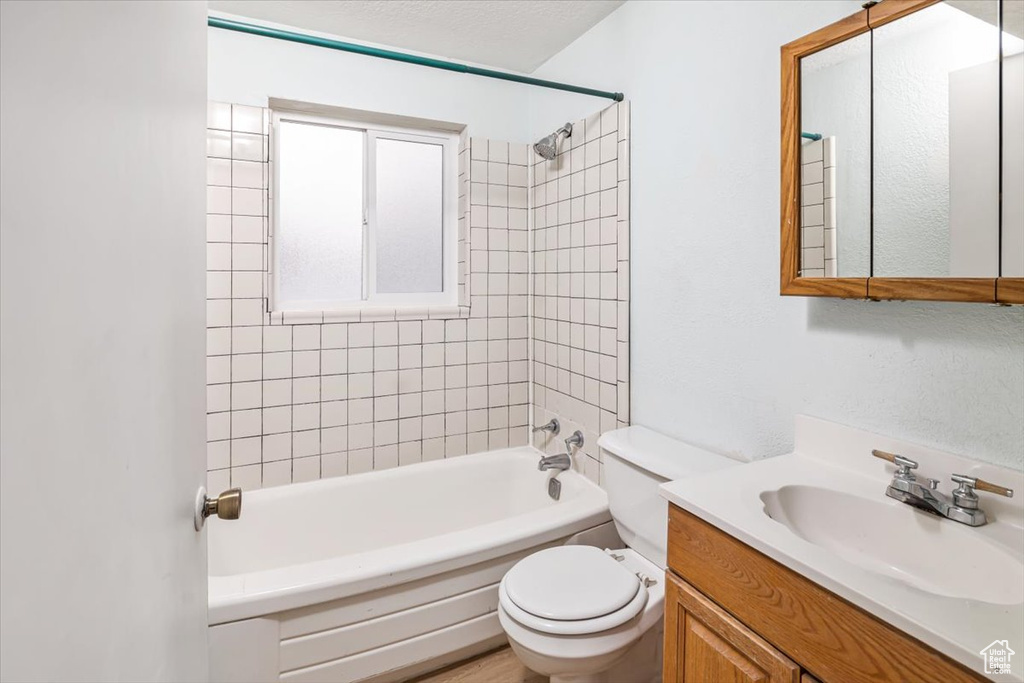 Full bathroom with tiled shower / bath, toilet, and large vanity