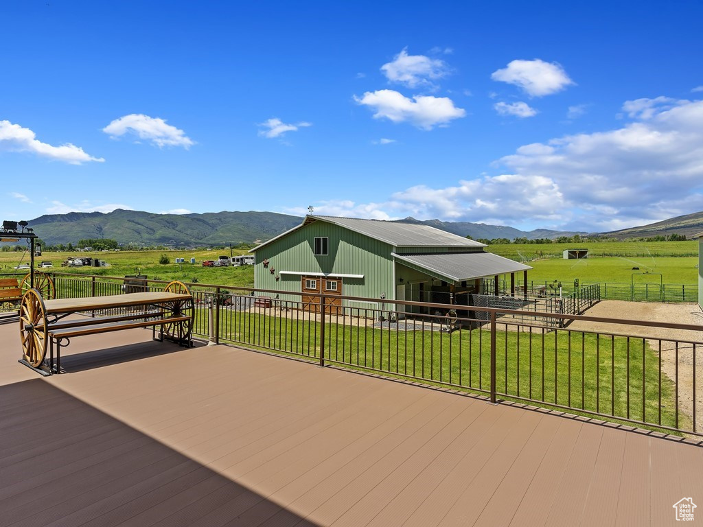 Deck with a rural view, a yard, and a mountain view