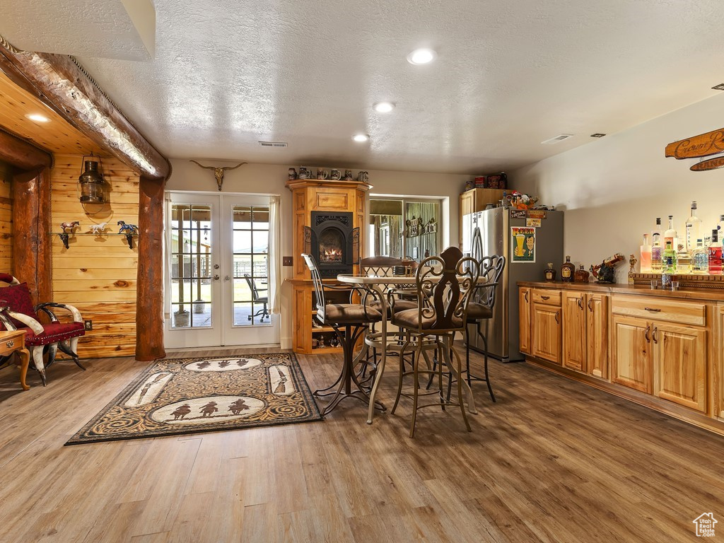 Dining area with wood-type flooring, wood walls, a textured ceiling, and french doors