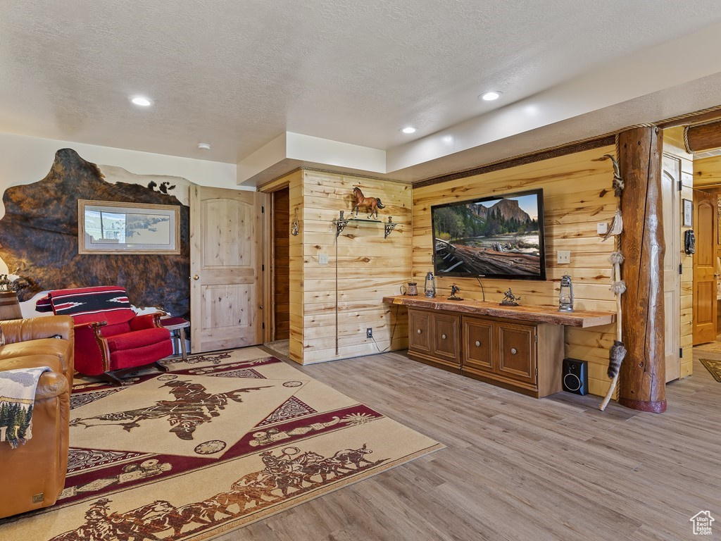 Living room featuring wood walls, light hardwood / wood-style flooring, and a textured ceiling