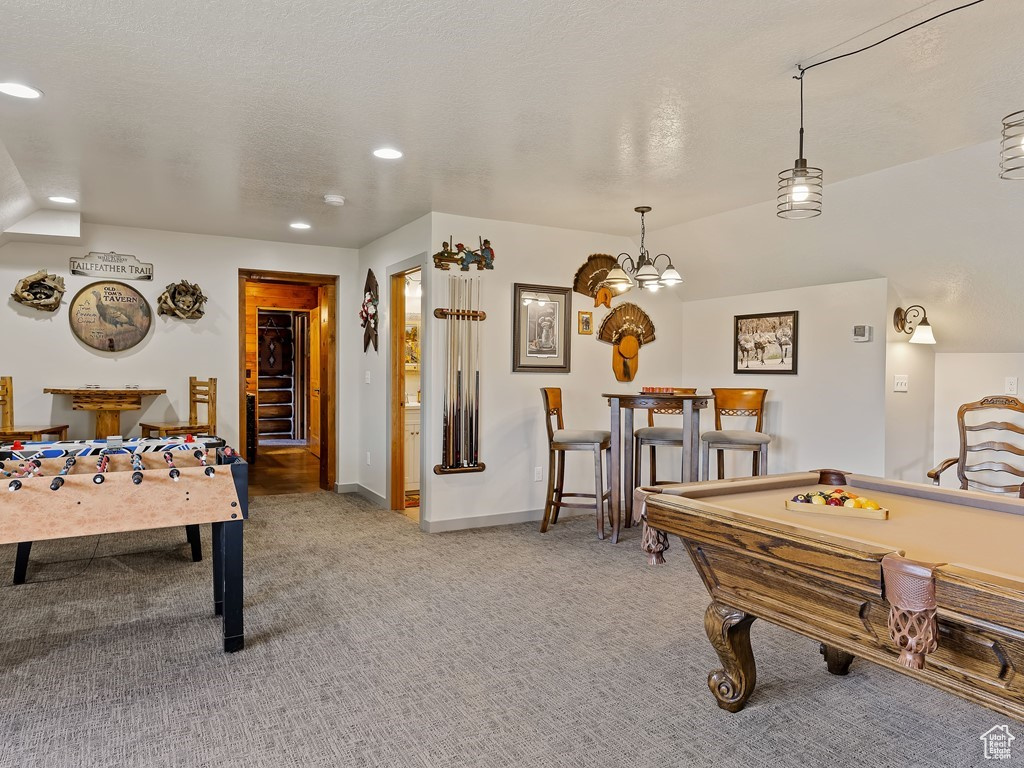Recreation room with an inviting chandelier, a textured ceiling, pool table, and light carpet