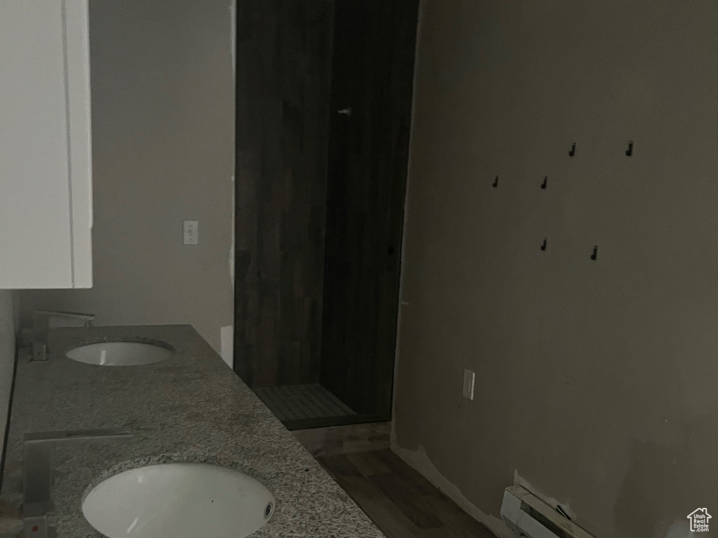 Bathroom featuring baseboard heating, dual vanity, and hardwood / wood-style floors