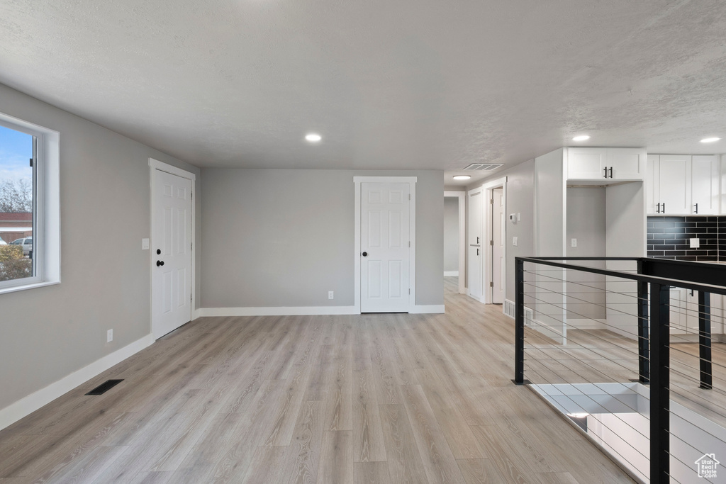 Interior space featuring tasteful backsplash, white cabinets, and light hardwood / wood-style flooring