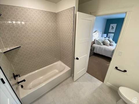 Bathroom featuring tiled shower / bath, tile floors, and toilet