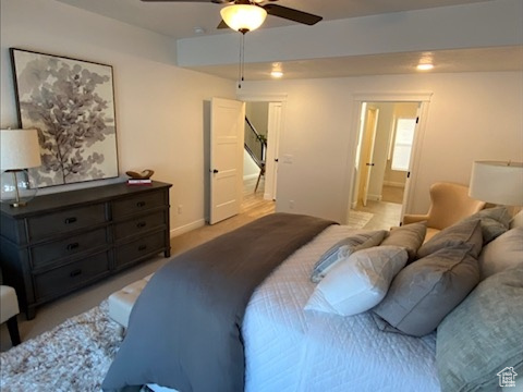 Bedroom featuring ensuite bath, ceiling fan, and light carpet