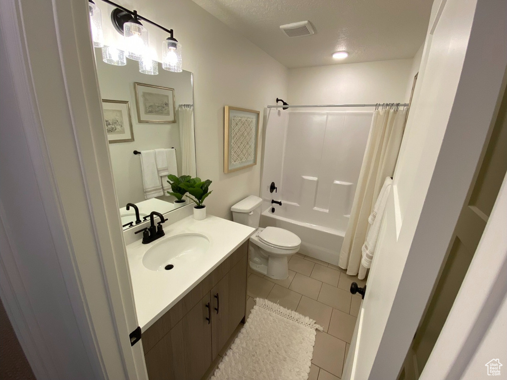 Full bathroom featuring tile floors, toilet, large vanity, and shower / tub combo