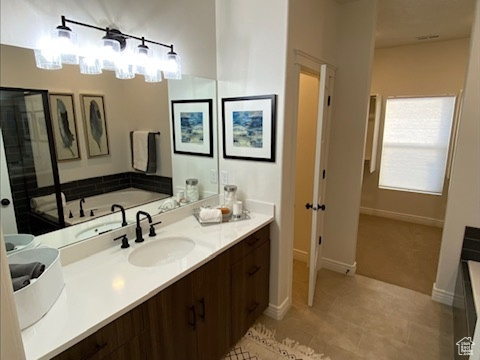 Bathroom featuring a washtub, tile floors, and vanity with extensive cabinet space