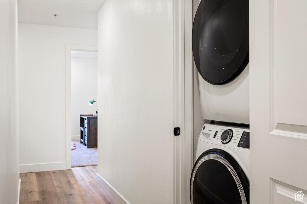 Clothes washing area featuring stacked washer and dryer and light colored carpet