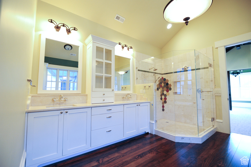 Bathroom featuring hardwood / wood-style flooring, dual vanity, lofted ceiling, and an enclosed shower