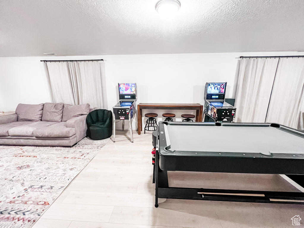Recreation room with light hardwood / wood-style floors, billiards, and a textured ceiling