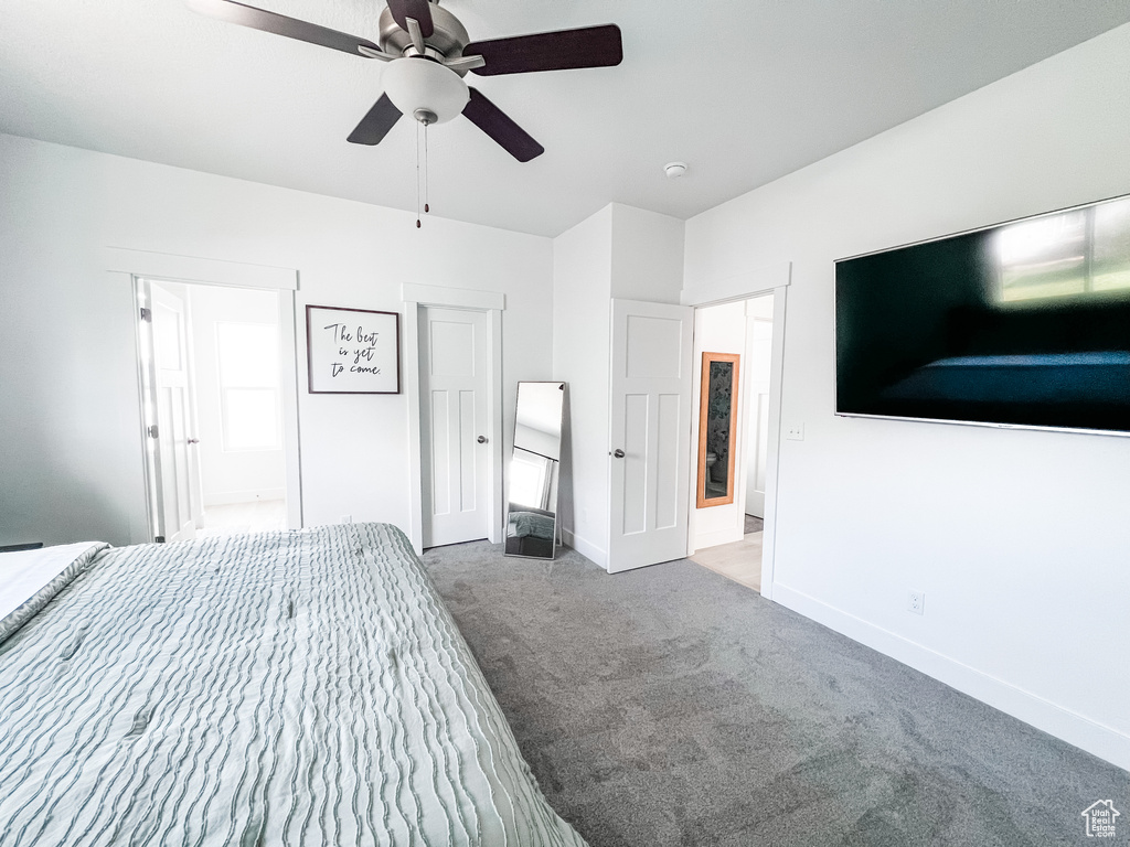 Unfurnished bedroom with dark carpet and ceiling fan