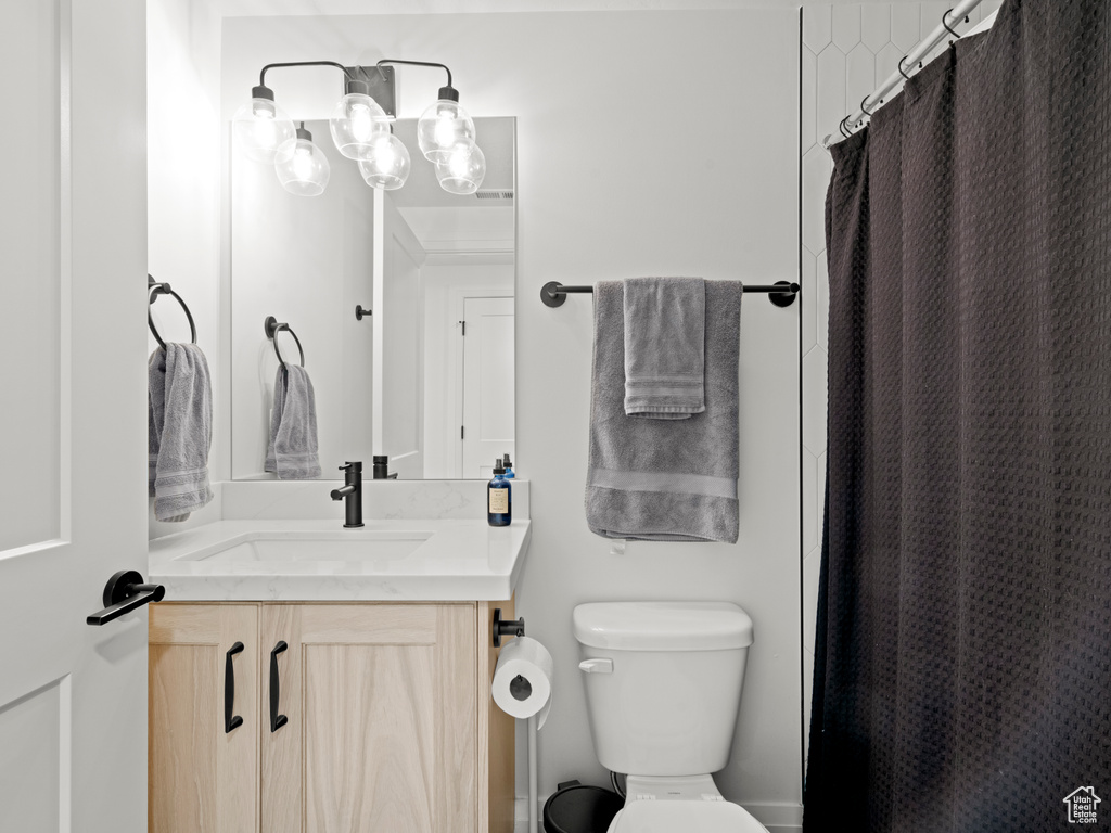 Bathroom with vanity, toilet, and an inviting chandelier