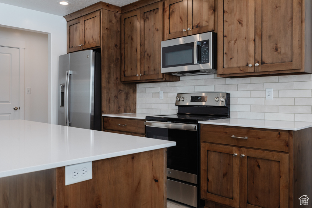 Kitchen featuring tasteful backsplash and appliances with stainless steel finishes