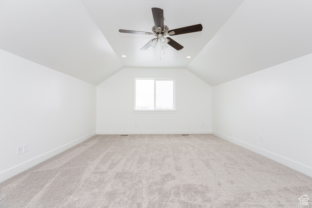 Additional living space featuring light carpet, ceiling fan, and lofted ceiling