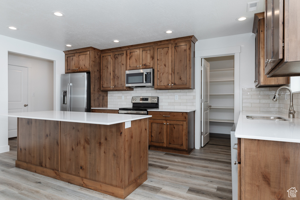 Kitchen featuring sink, stainless steel appliances, light hardwood / wood-style flooring, and backsplash