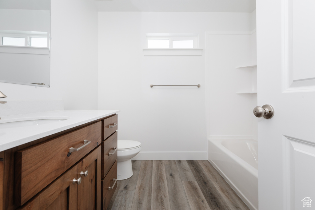 Full bathroom with plenty of natural light, vanity, toilet, and hardwood / wood-style floors