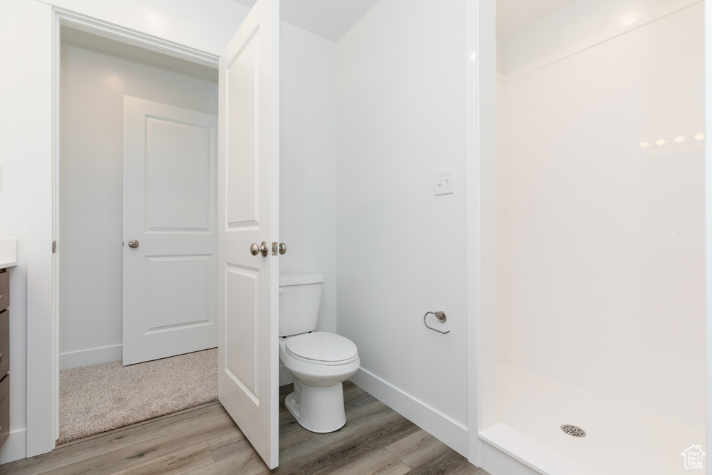 Bathroom featuring toilet, vanity, hardwood / wood-style flooring, and walk in shower