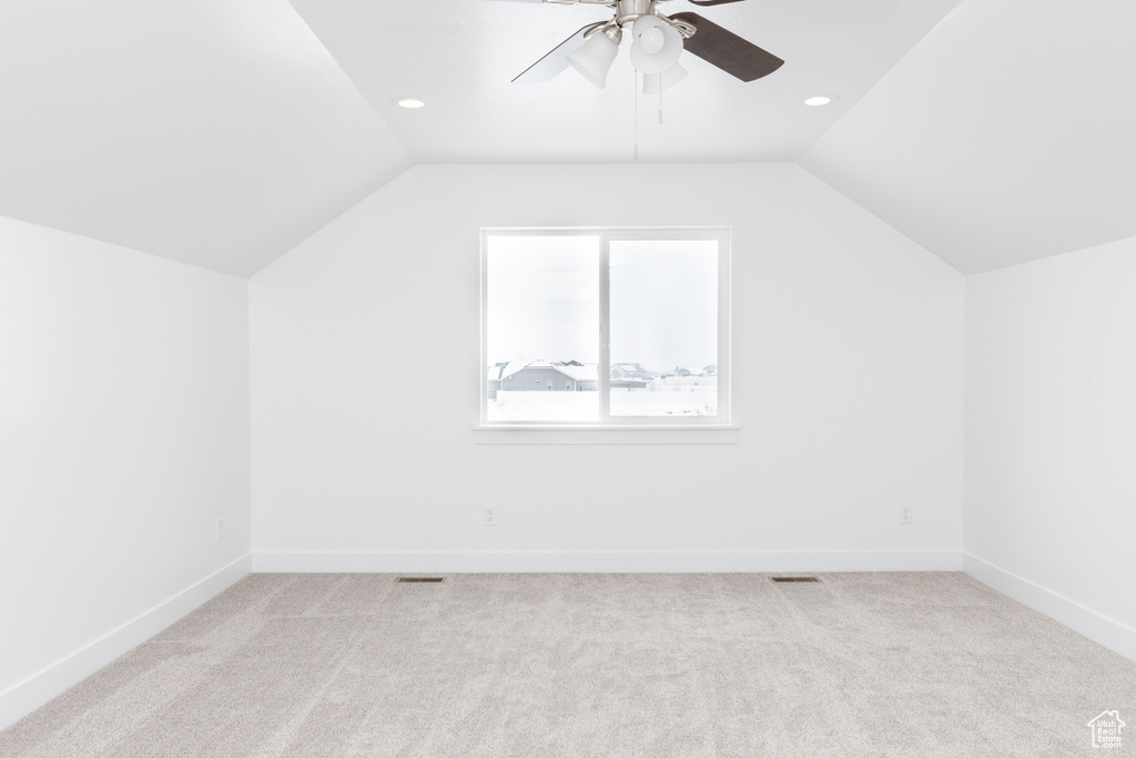 Additional living space with light colored carpet, lofted ceiling, and ceiling fan