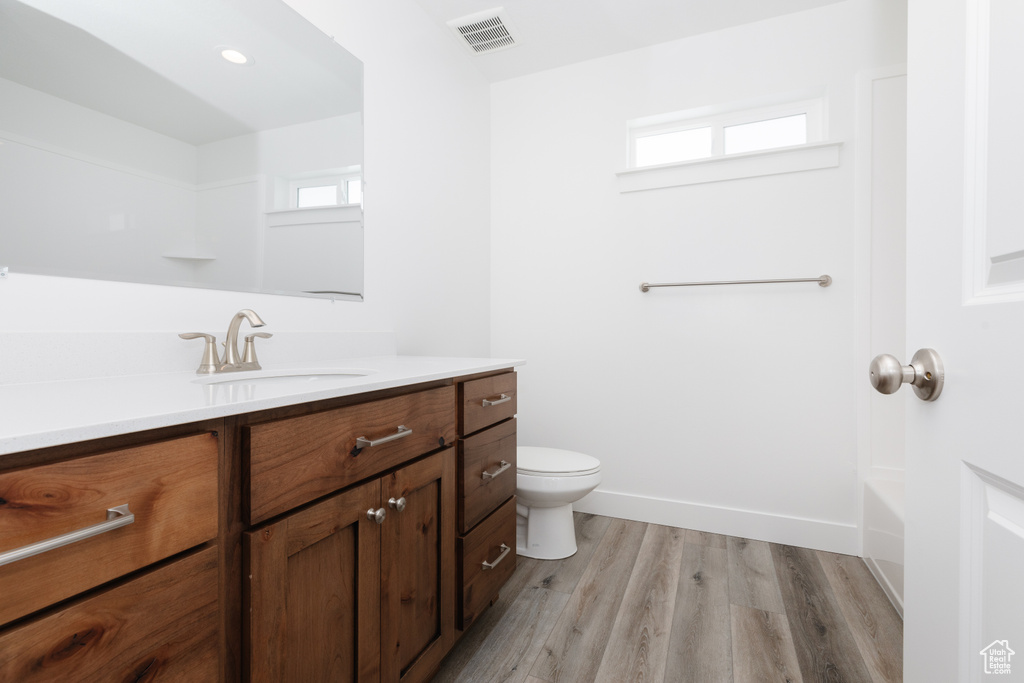 Full bathroom featuring vanity, toilet, hardwood / wood-style floors, and a healthy amount of sunlight