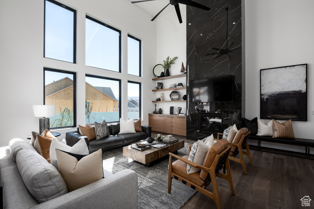 Living room featuring a high ceiling, dark wood-type flooring, and ceiling fan