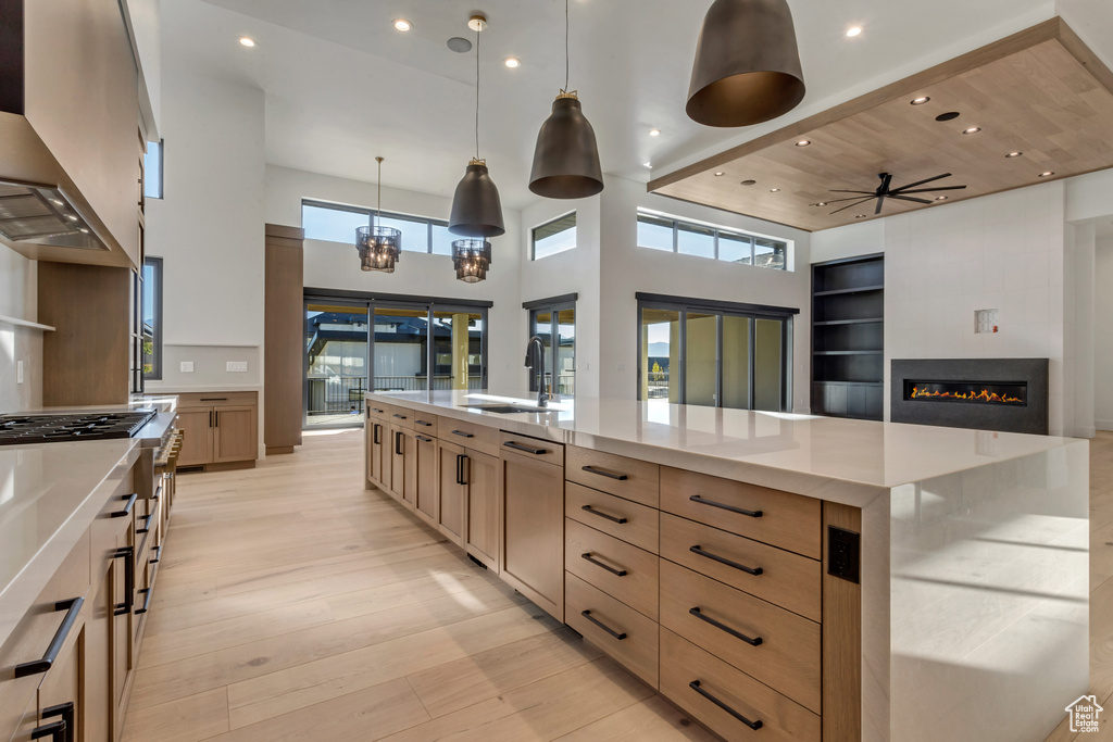 Kitchen with ceiling fan with notable chandelier, hanging light fixtures, light hardwood / wood-style flooring, sink, and wood ceiling