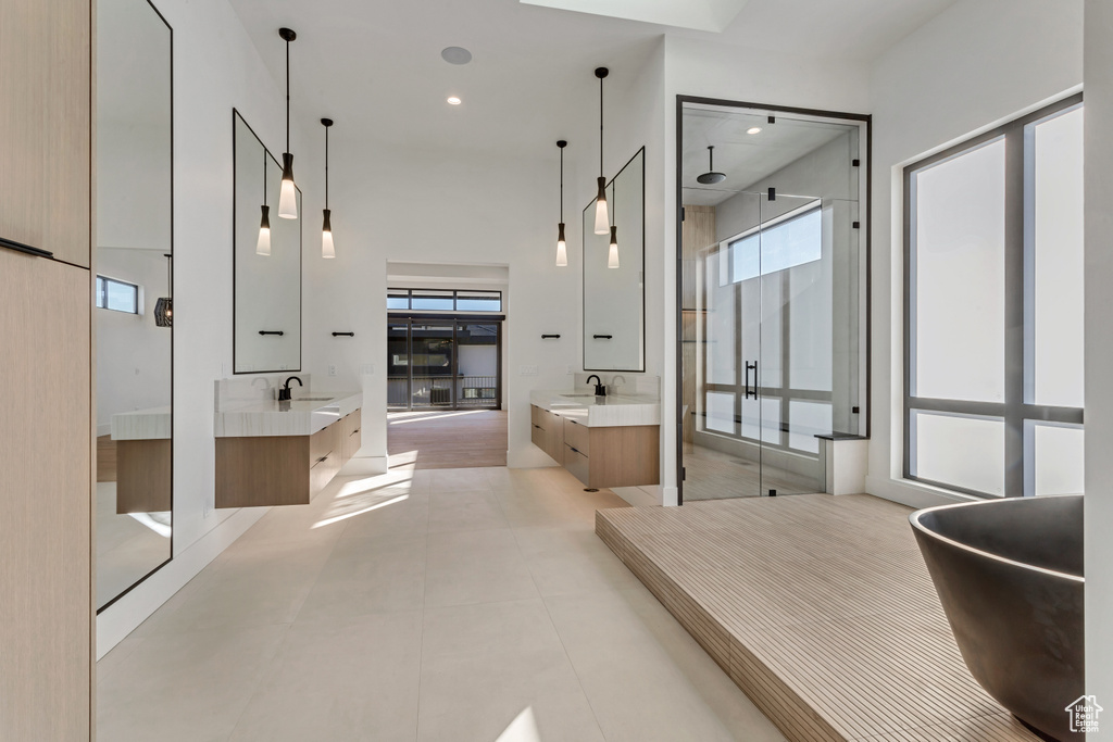 Bathroom with tile floors, a wealth of natural light, a tub, and dual bowl vanity