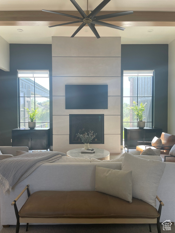 Living room featuring a tiled fireplace, a wealth of natural light, and ceiling fan