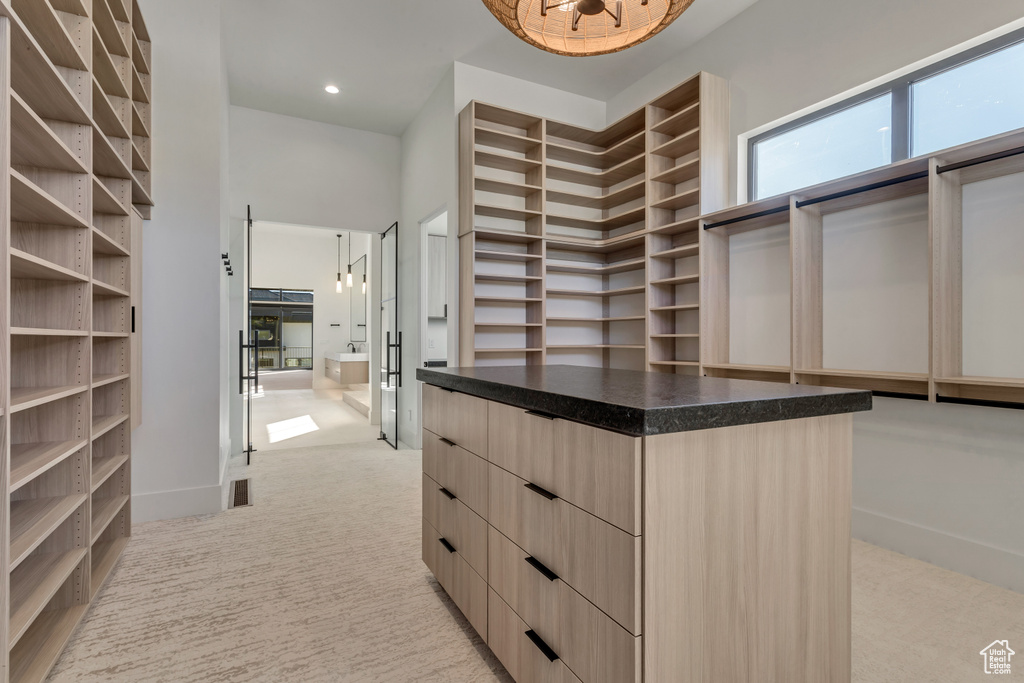 Spacious closet with light carpet and a towering ceiling