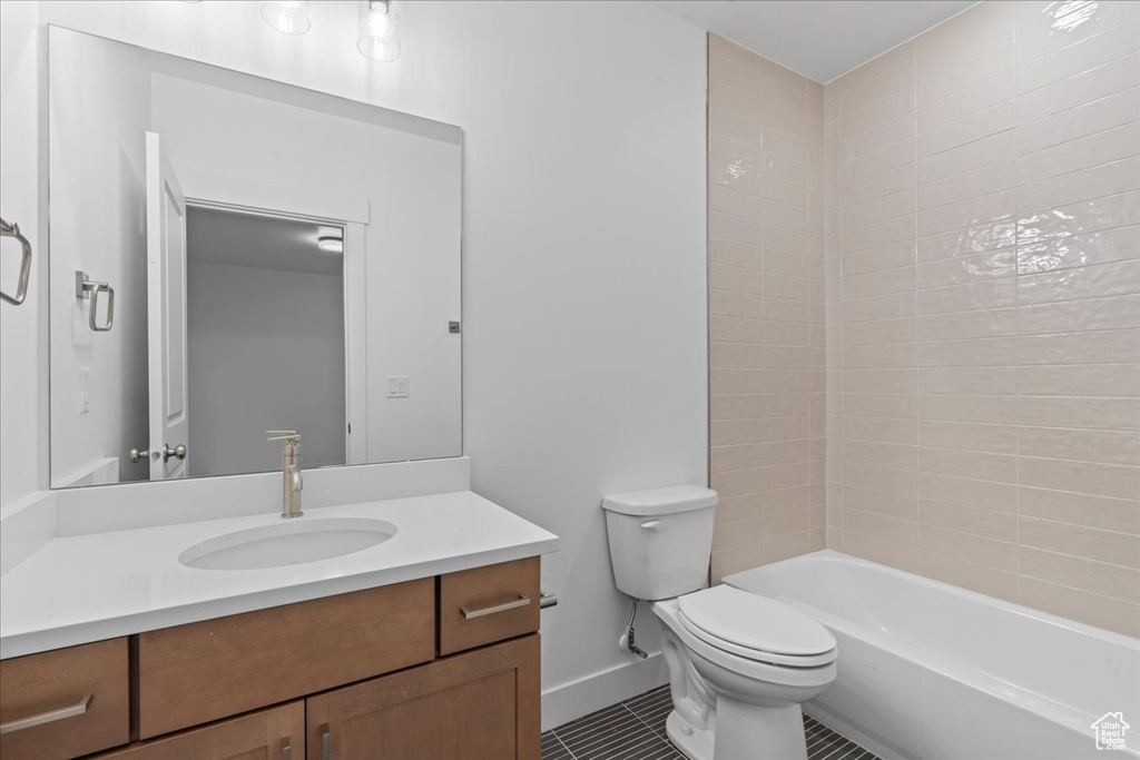 Full bathroom with vanity, tiled shower / bath combo, toilet, and tile patterned floors