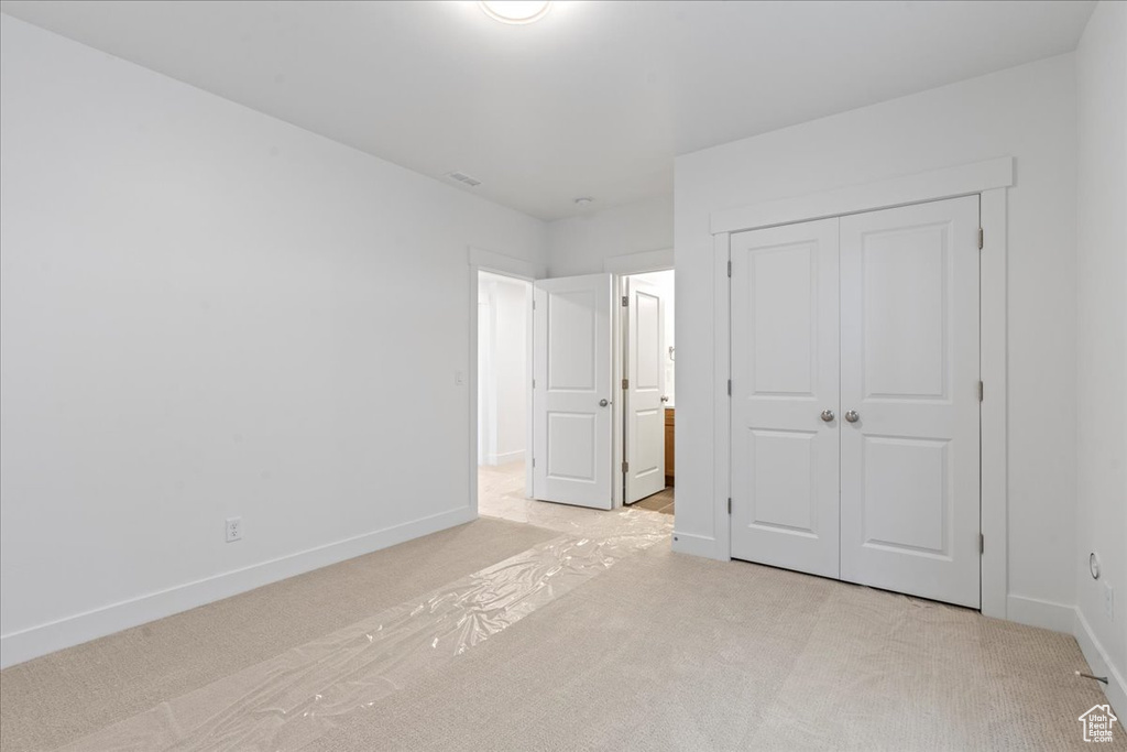 Unfurnished bedroom with a closet and light colored carpet