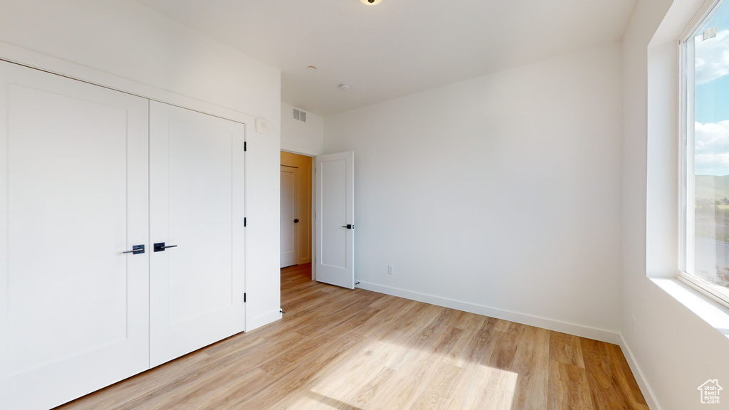 Unfurnished bedroom with a closet and light hardwood / wood-style floors