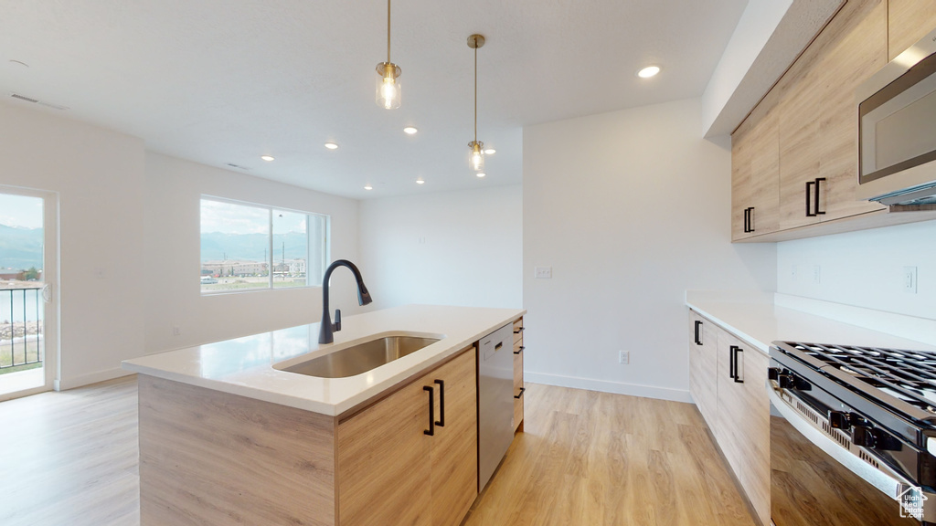 Kitchen with pendant lighting, sink, light hardwood / wood-style floors, and plenty of natural light